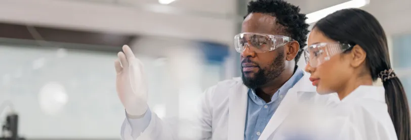 man and woman wearing lab coats and protective glasses