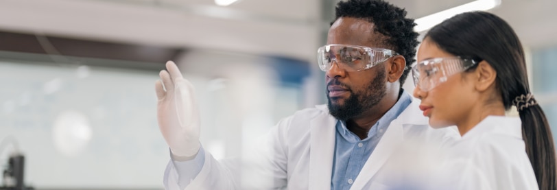 man and woman wearing lab coats and protective glasses